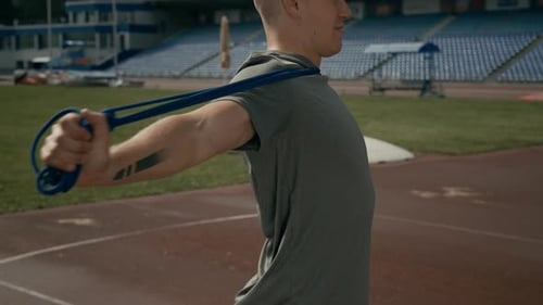 Young Adult Exercising with Resistance Band on Track