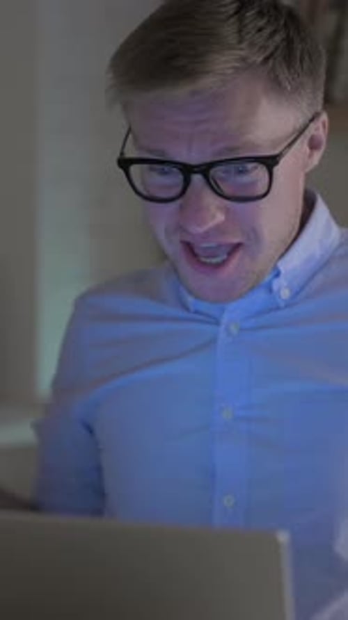 Excited Man with Glasses Celebrates Good News on Laptop