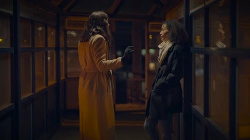 Two Women Conversing at Night in Walkway