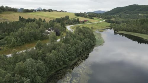 Upwards movement from the calm reflective lake in Norway over the road towards the green grass cover