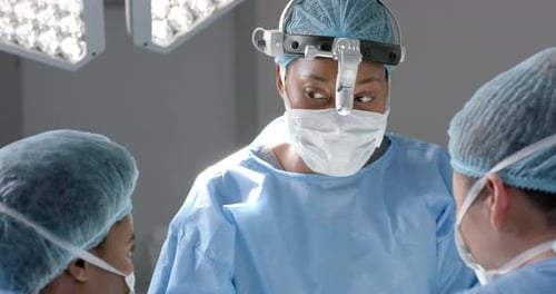 Diverse female surgeons operating on patient in operating theatre, slow motion