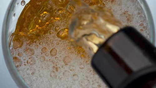 Bottle Pouring Craft Beer in Transparent Glass Closeup. Lager Stream Making Foam