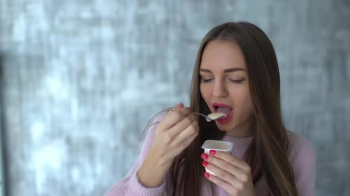 Woman Enjoys Eating Yogurt with Spoon in a Home