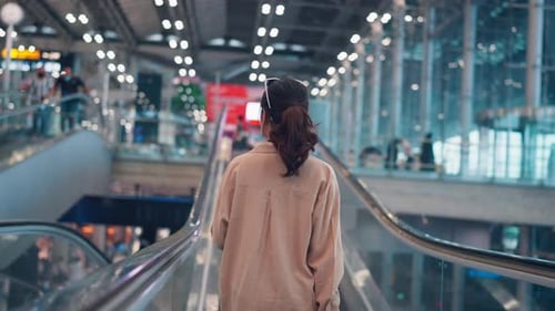 Asian tourist woman traveller with simple suitcase stand on moving walkway in airport terminal