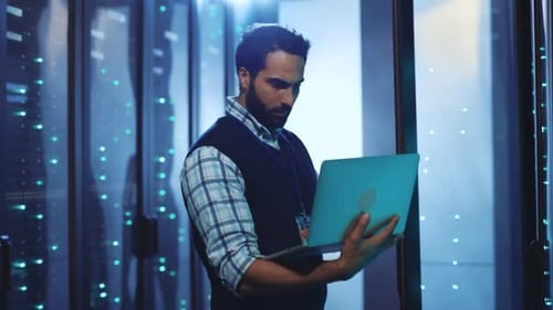 Man Using Laptop in a Server Room