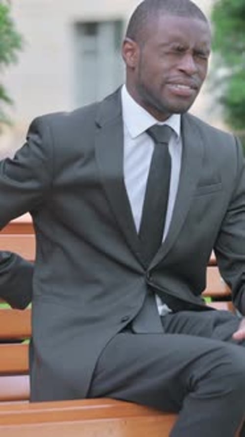 Man in Suit Experiences Back Pain on Bench