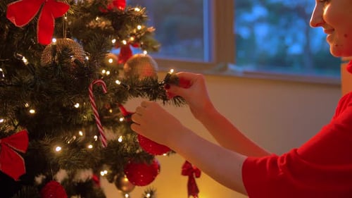 Woman Decorating Christmas Tree with Red Baubles