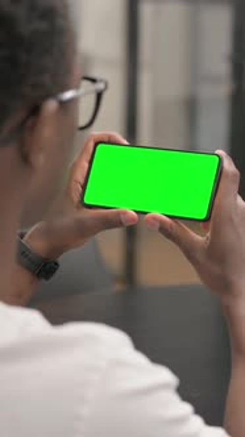 Close up of African Man Holding Phone Horizontal with Green Screen