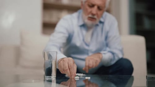 Elderly Man Taking Medication with Water in Home