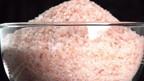 Pink himalayan salt or rock salt rotating in glass bowl. Trace minerals salt used for cooking