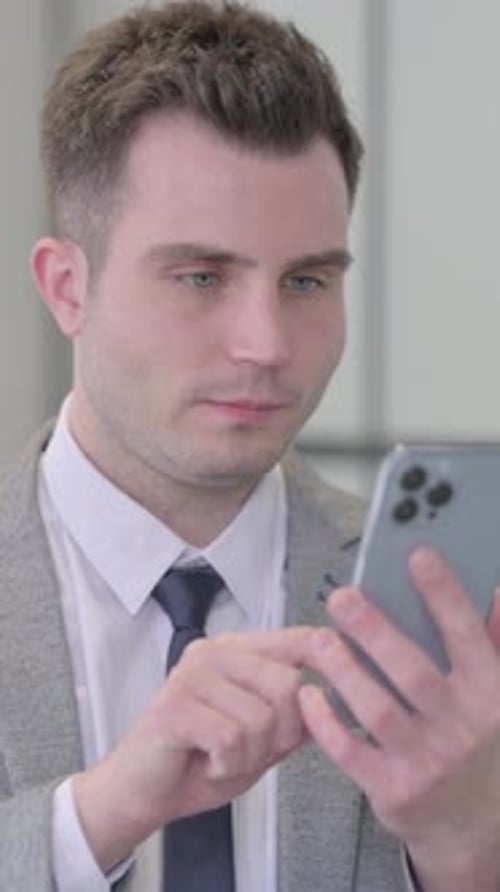 Man in Suit Uses Smartphone in Indoor Setting