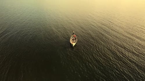 Pair of isolated anglers fishing remote on an Irish lough boat with the setting golden hour sun refl