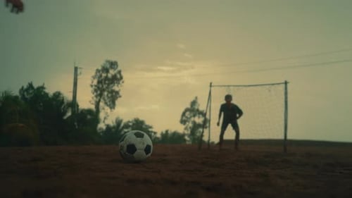 Goalkeeper blocking penalty kick on a dirt field with intense slow-motion action