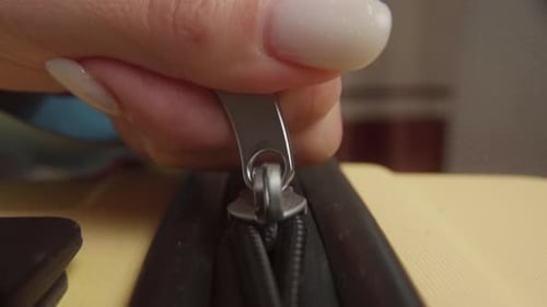 Hand Operating Zipper of Yellow Bag Close Up