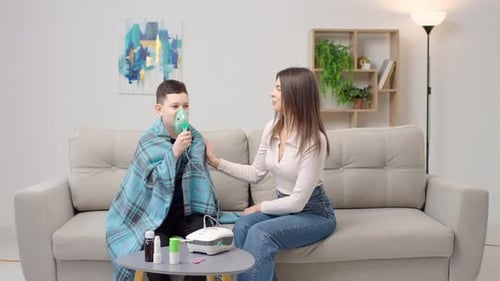 Boy Using Nebulizer Assisted by Woman at Home