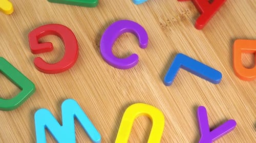 Multicolored letters rotate on a wooden background. The concept of learning, school or college
