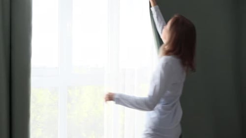 Woman Closing Bedroom Curtains in the Morning