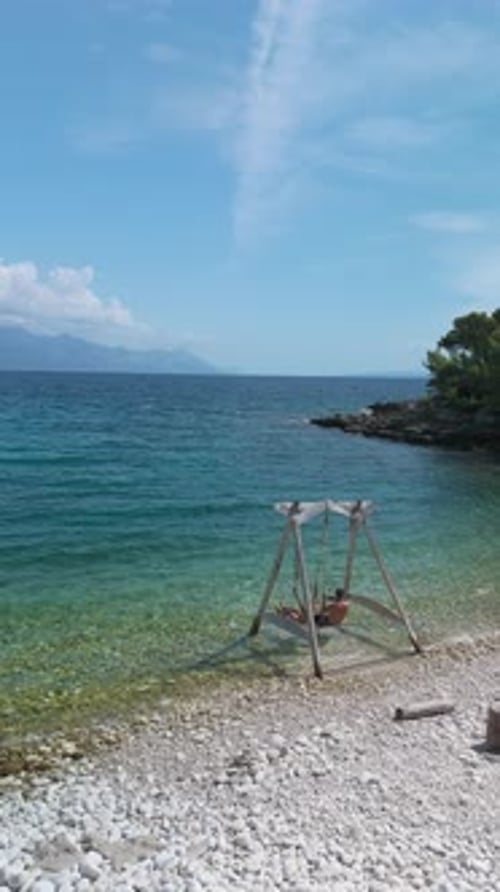 Enjoying a Sunny Day on the Swings By the Tranquil Sea with Friends in Summer Paradise in Croatia