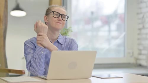 Woman Massaging Wrist At Desk In Office