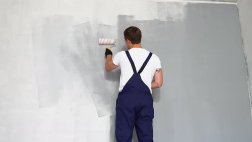Man Paints Wall Gray Indoors