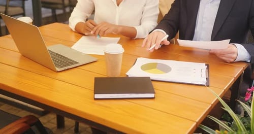 Business Partners Analyse Papers for Project at Cafe Table