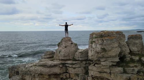 aerial man standing rocks sea