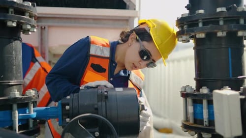 female engineer in safety gear inspects and maintains industrial water piping system valves