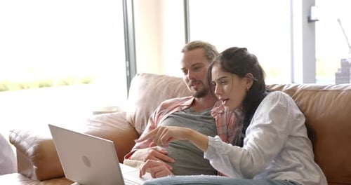Couple Using Laptop Together on Sofa at Home