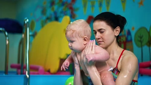 Healthy gymnastics in the water for baby boy. Female coach deeps the kid into the swimming pool.