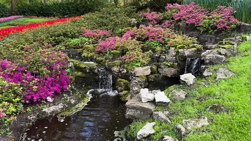 Ein wunderschöner üppiger Garten mit fließenden Wasserfällen, umgeben von farbenfrohen Blumen