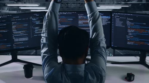 Rückansicht eines müden asiatischen Entwicklers, der sich beim Schreiben von Code im Rechenzentrum streckt