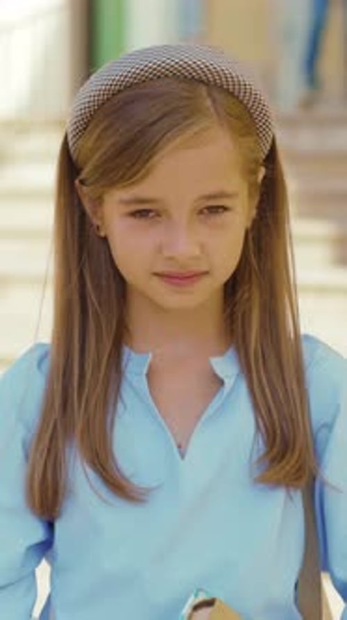 A Young Girl Who is Wearing a Stylish Headband is Holding a Book