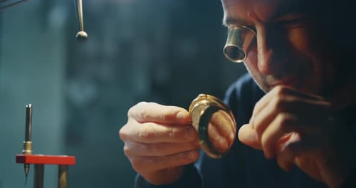 Slow motion close up of a professional watchmaker repairer working on an old vintage pocket watch