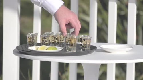 Hand Arranging Shot Glasses with Lime on Tray