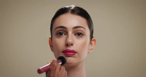 Woman, makeup artist and brush in studio with foundation, beauty and application on background