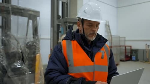 Engineer Uses Laptop Looking Around Premise of Warehouse