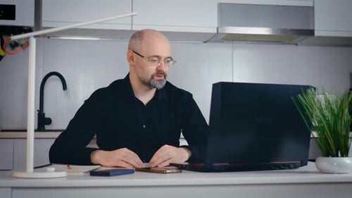 Man Works on Laptop at Kitchen Counter