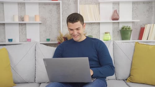 Young Man Uses Laptop Computer at Home