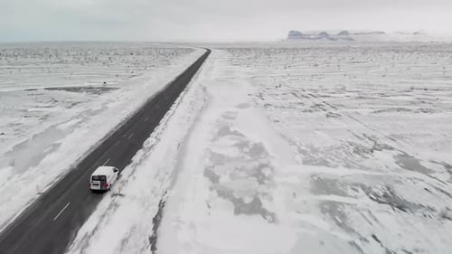 Aerial shooths of a van on Iceland road. Is winter and snow is all over the road.
