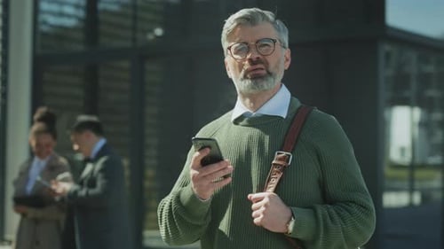 Man in Green Sweater Outdoors Casual Professional Pauses Outside Office in Daylight with Colleagues
