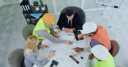 Top view of diverse team of engineers man and woman managers over building project in meeting room