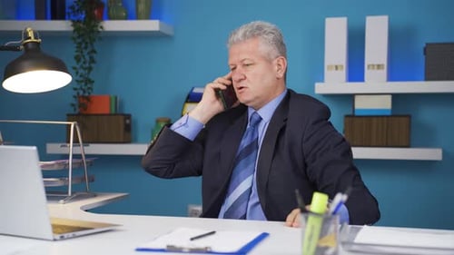 Frustrated Man Talking on Phone in Workplace