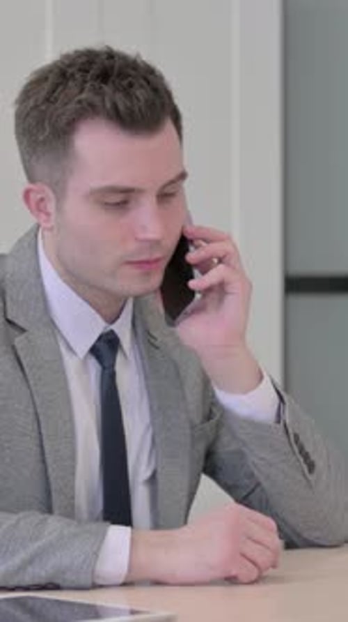 Young Businessman Talking on Phone in Office, vertical video