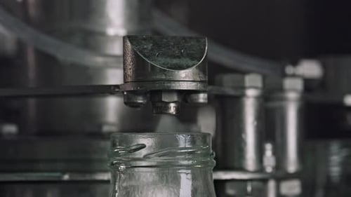 Machine d'embouteillage industrielle capsulant des bouteilles en verre sur une chaîne de montage