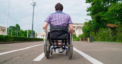 Man Wheeling Himself in a Wheelchair Outdoors
