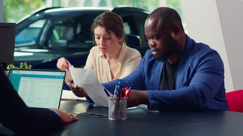 Customers in Dealership Completing Necessary Car Payment Paperwork