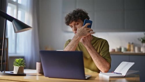 Young Adult Working at Desk With Phone and Laptop