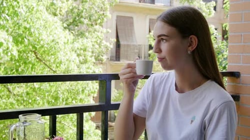 Woman Drinking Coffee on a Balcony