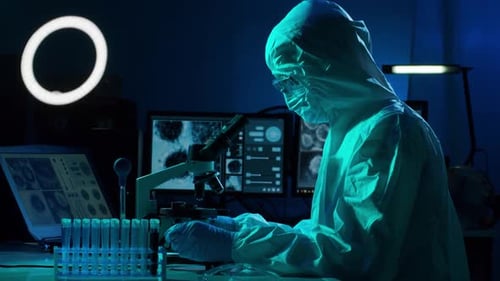 Scientist Researching Under Microscope in Dark Laboratory