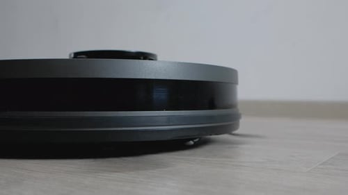 Robotic Vacuum Cleaner Moves Across Wooden Floor